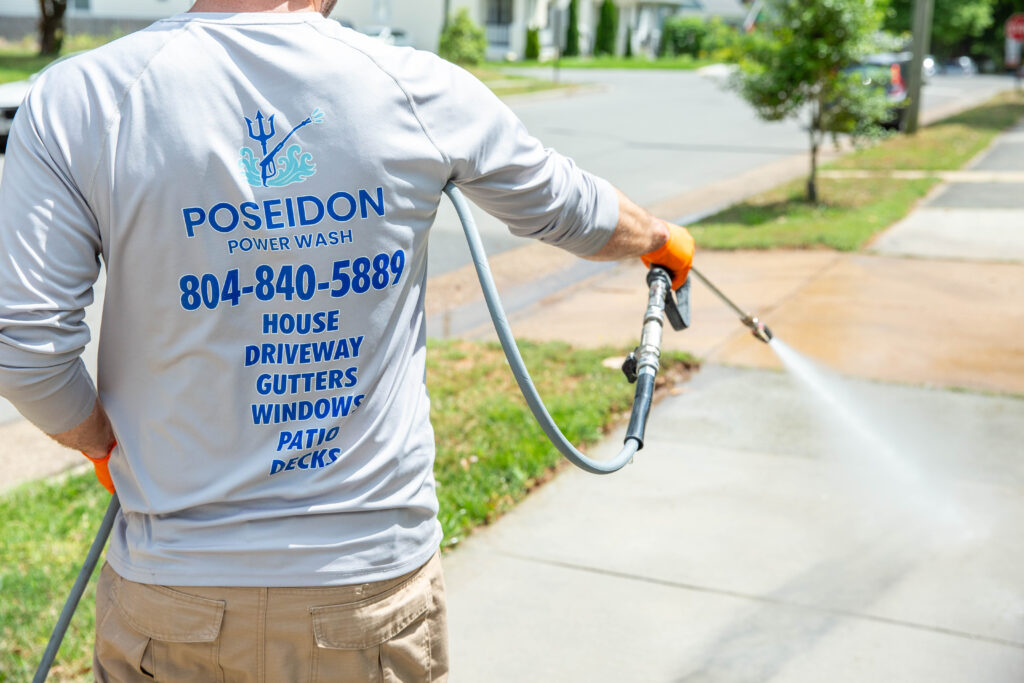 Poseidon Power Wash technician pressure washing a concrete driveway in Richmond VA